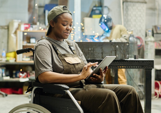 A woman sitting in a wheelchair uses her tablet to check the disability cover payout she received. A woman in a wheelchair uses a tablet to access a disability cover payout paid into her bank account.